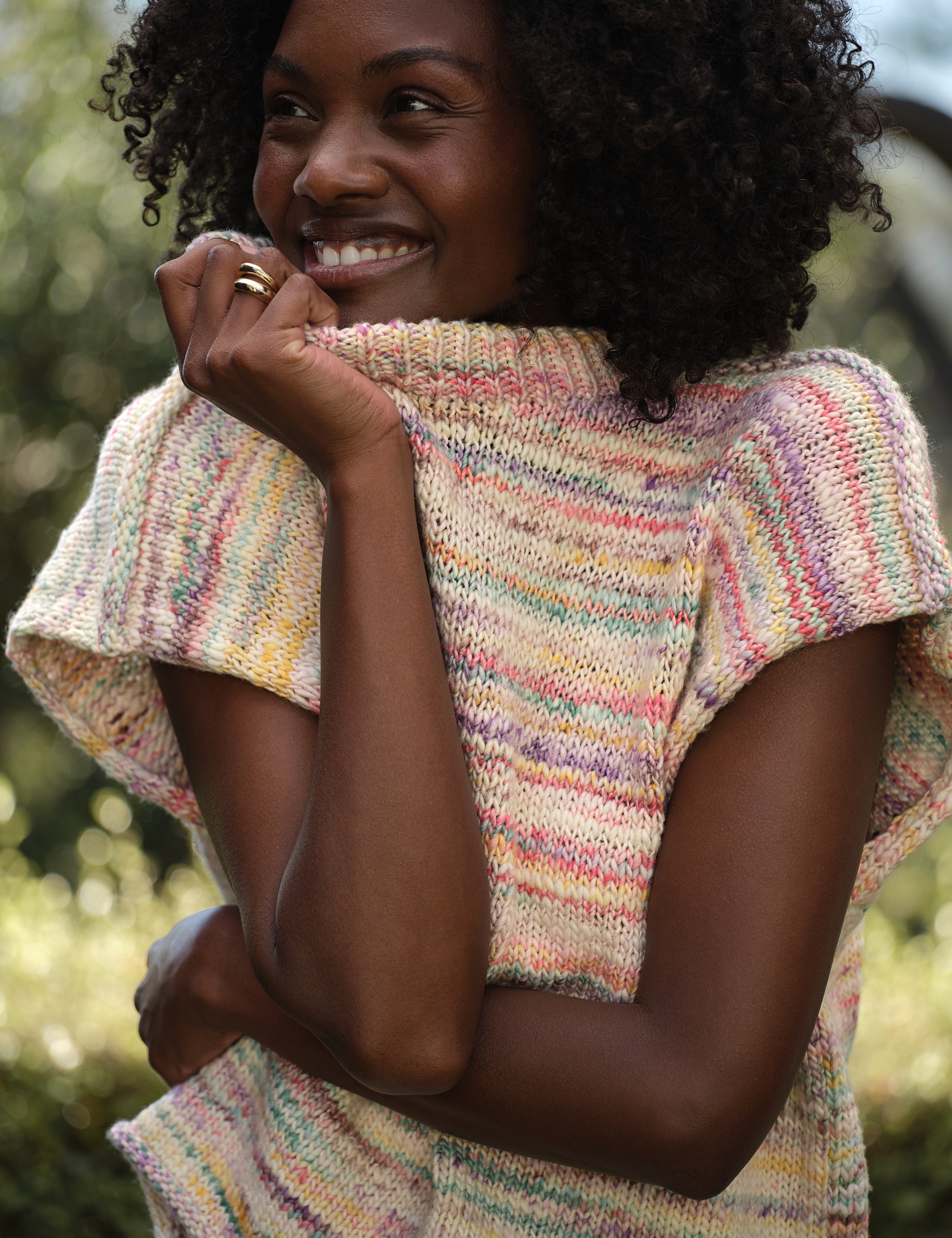 Woman wearing a colorful knitted vest with a blurred natural background, view 3
