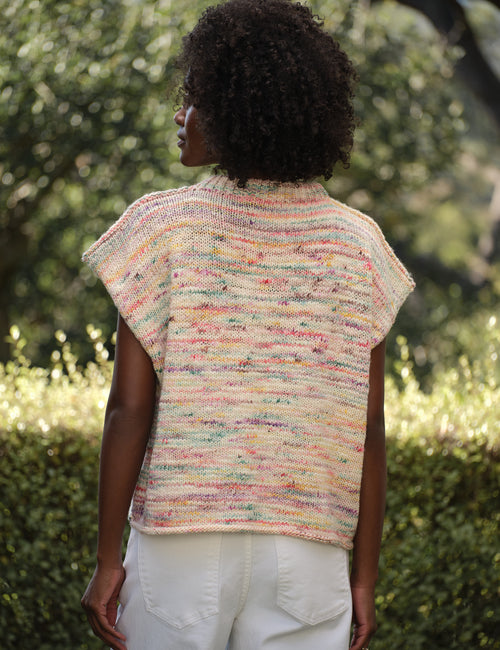 Person wearing a colorful knitted vest in an outdoor setting, alternate view