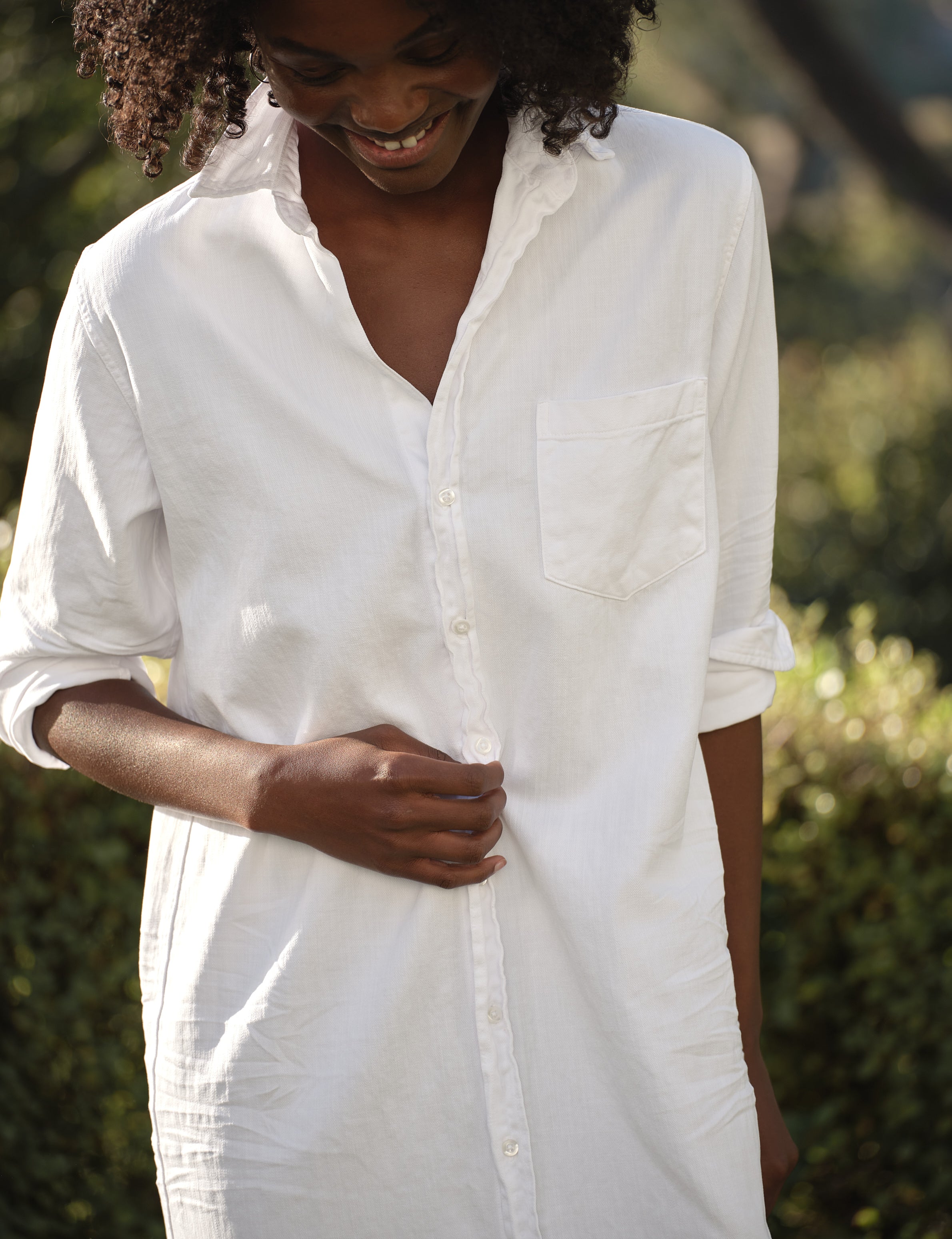 Person wearing a white dress outdoors with greenery in the background, view 3
