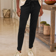 Person wearing black pants and white sneakers in a home setting