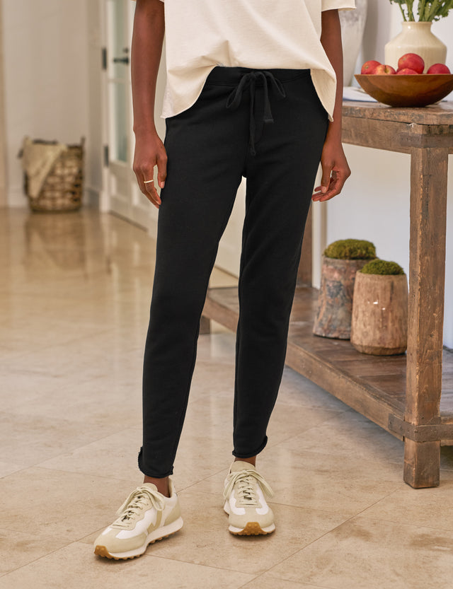 Person wearing black pants and white sneakers in a home setting