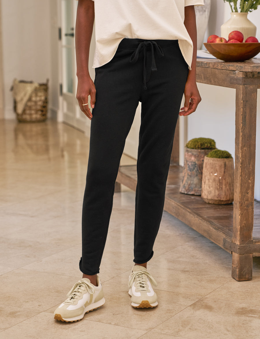 Person wearing black pants and white sneakers in a home setting