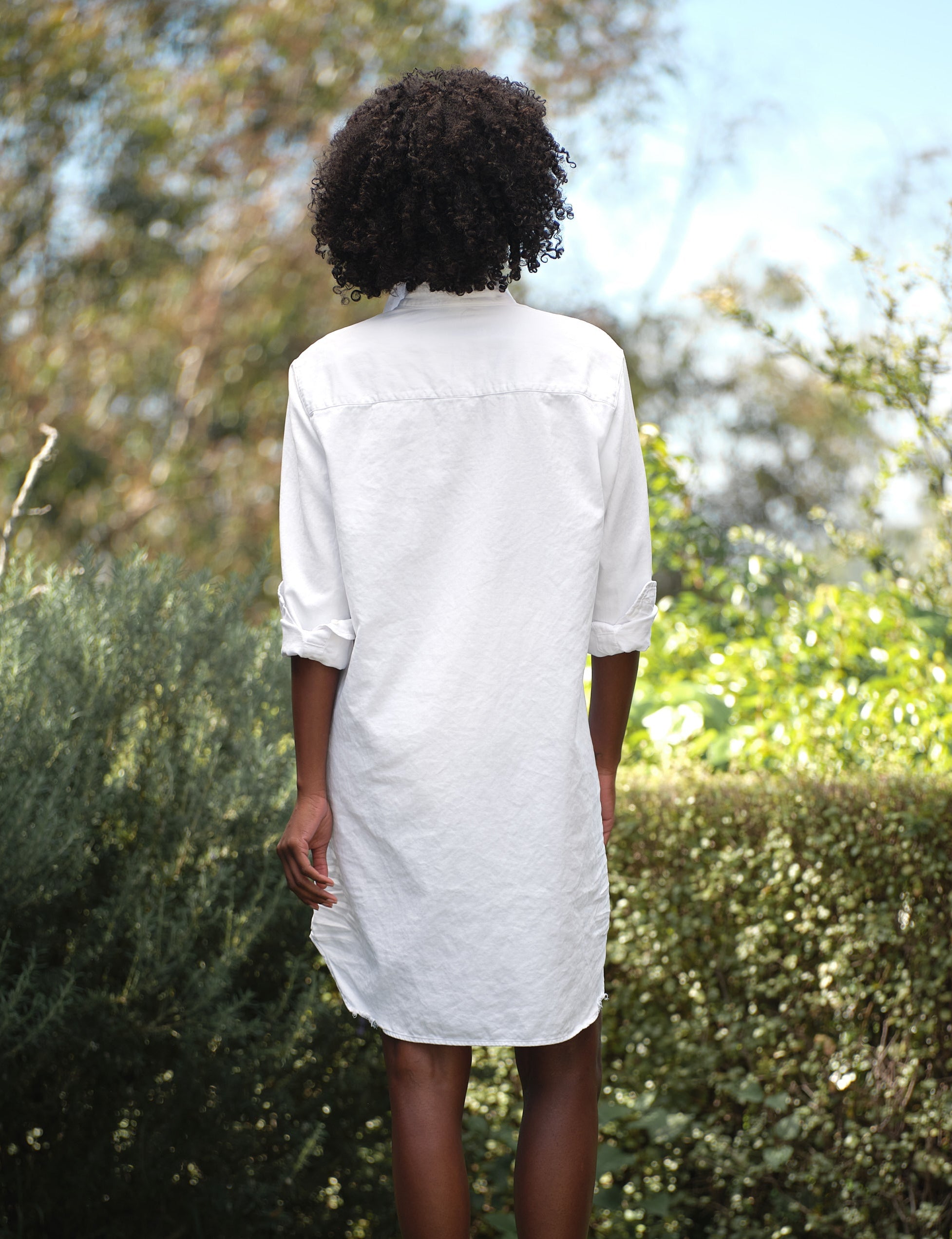 Person wearing a white dress standing in a garden, alternate view
