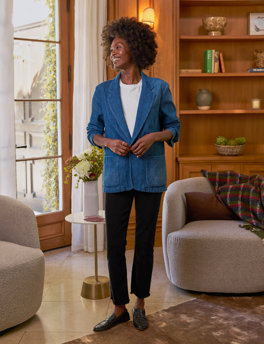 Woman standing in a living room wearing a blue blazer.
