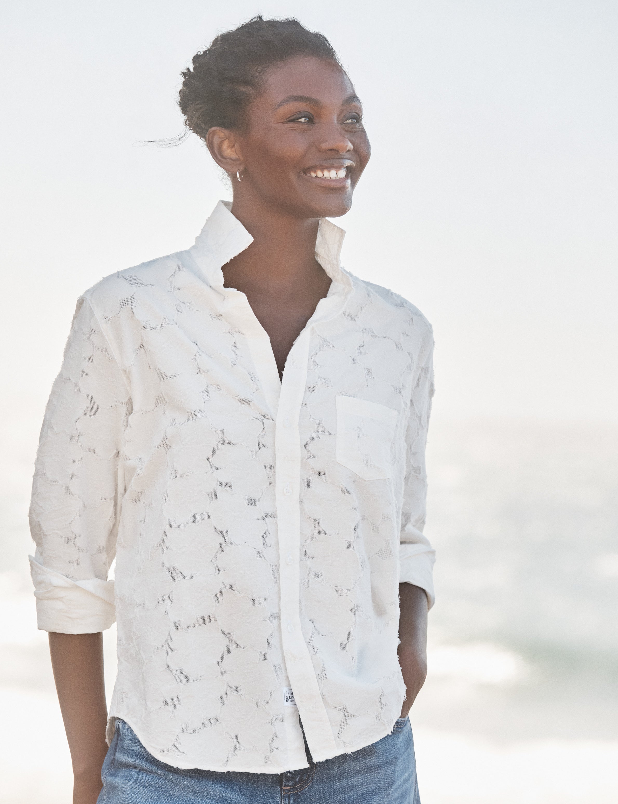 Woman wearing a white patterned shirt with a blurred background, front view