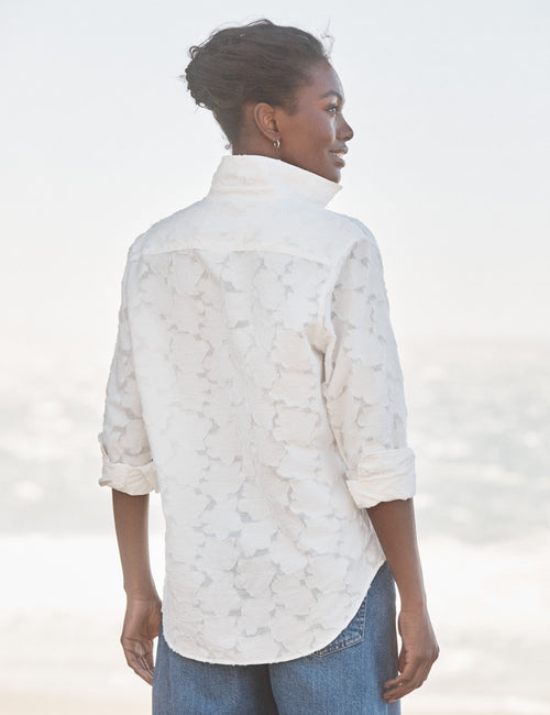 Woman wearing a white lace blouse with a blurred background, alternate view