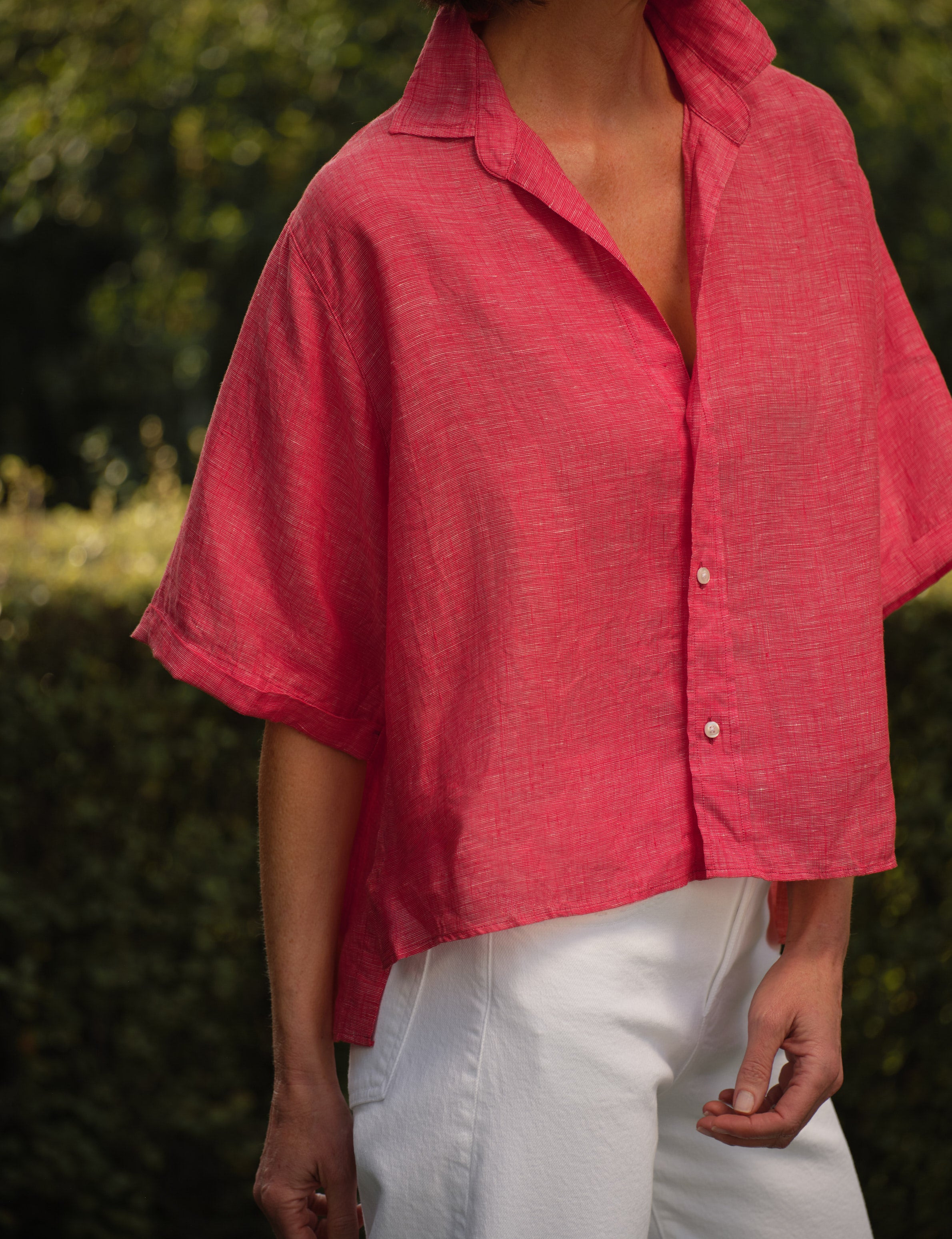 Person wearing a red shirt with short sleeves and white pants outdoors., view 3