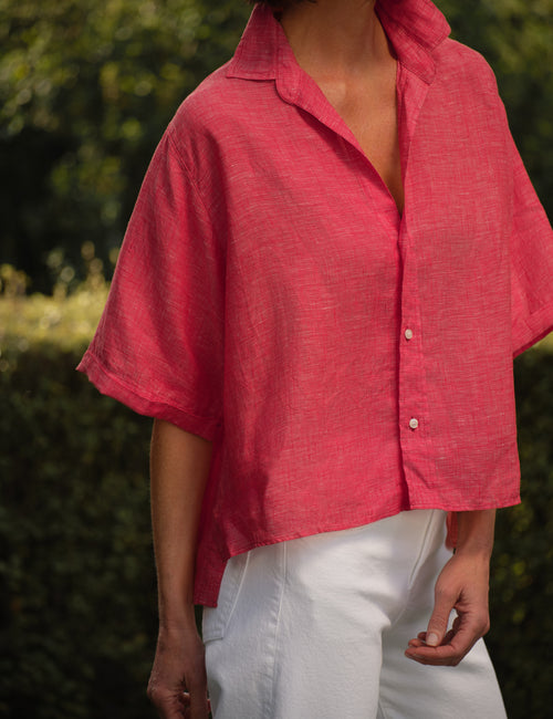 Person wearing a red shirt with short sleeves and white pants outdoors., view 3