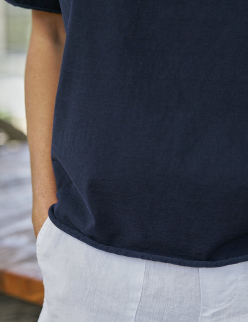 Person wearing a navy blue shirt with a blurred background, view 3