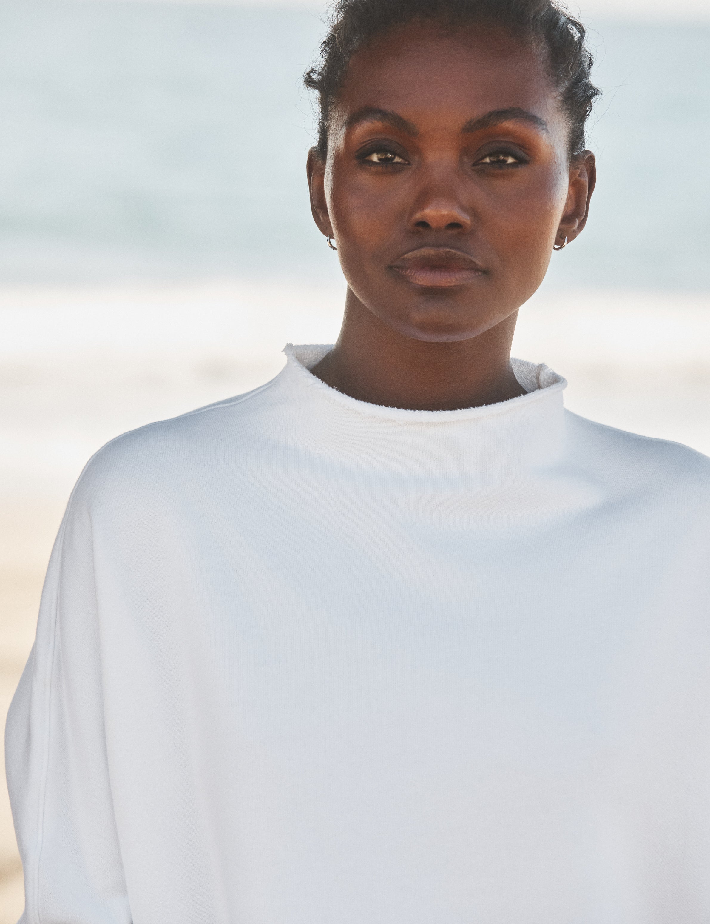 Woman wearing a white shirt against a blurred natural background, view 3