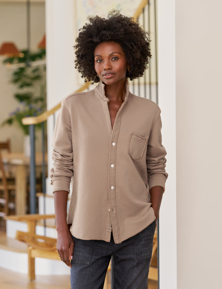 Woman wearing a beige button-up shirt and jeans indoors