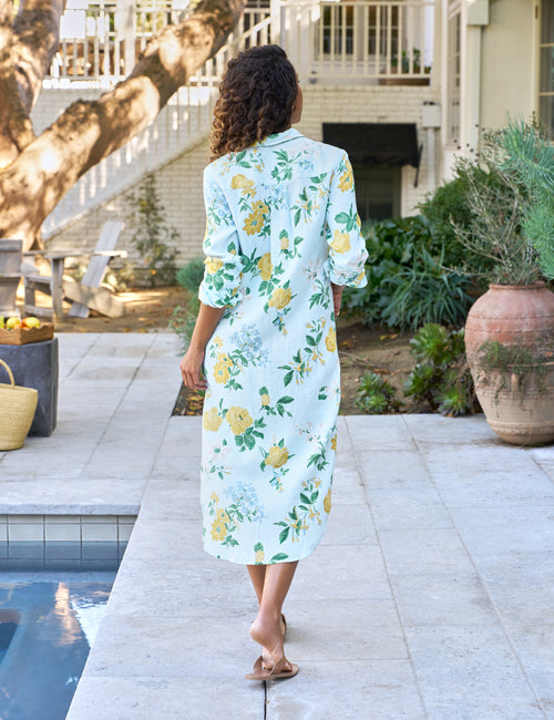 Woman in a floral dress standing by a poolside, view 3