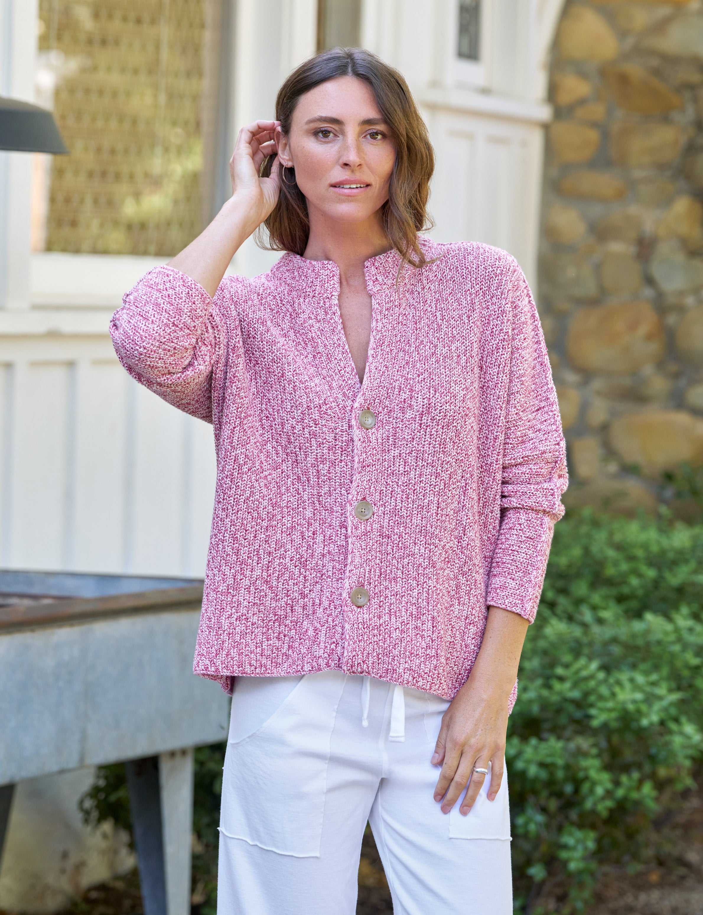 Woman wearing a pink blouse with a patterned design outdoors., front view