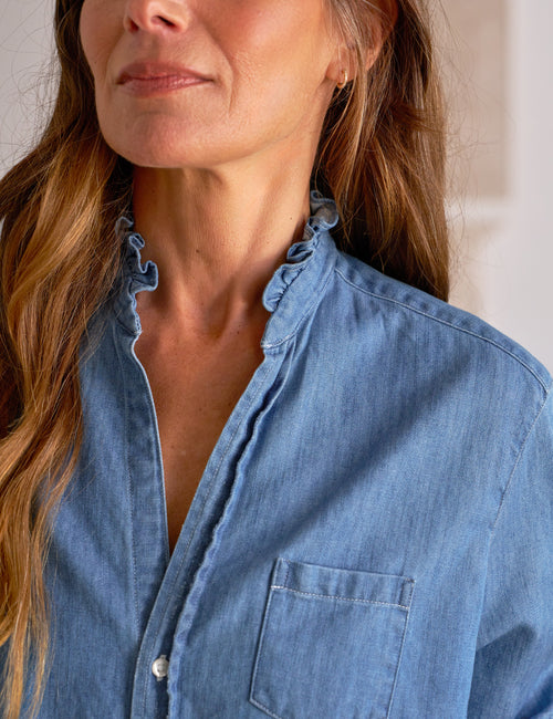 Woman wearing a blue denim shirt with a neutral background, view 3