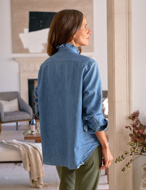 Woman wearing a blue denim shirt in a living room setting, alternate view