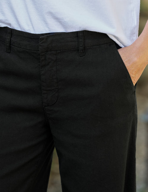 Person wearing black pants with a blurred background, view 3