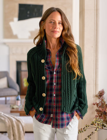 Woman wearing a green cardigan over a plaid shirt in a home setting