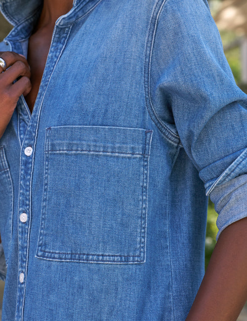 Close-up of a person wearing a blue denim shirt with a blurred background, view 3