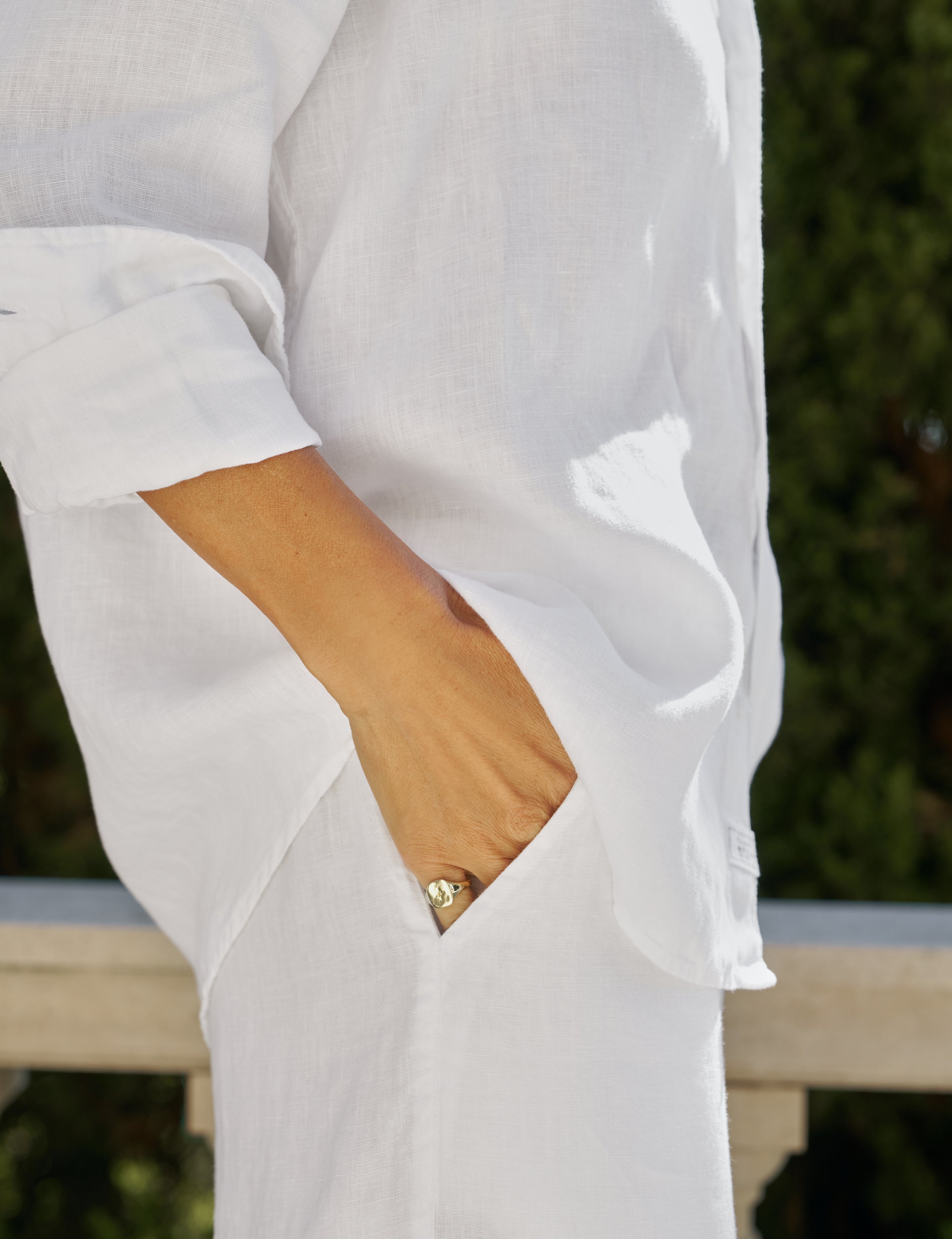 Close-up of a person wearing a white outfit with a blurred natural background