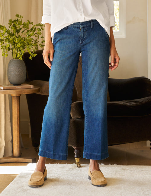 A person standing in a room wearing Italian Dream Light Denim pants and a white top, with tan shoes and socks visible., front view