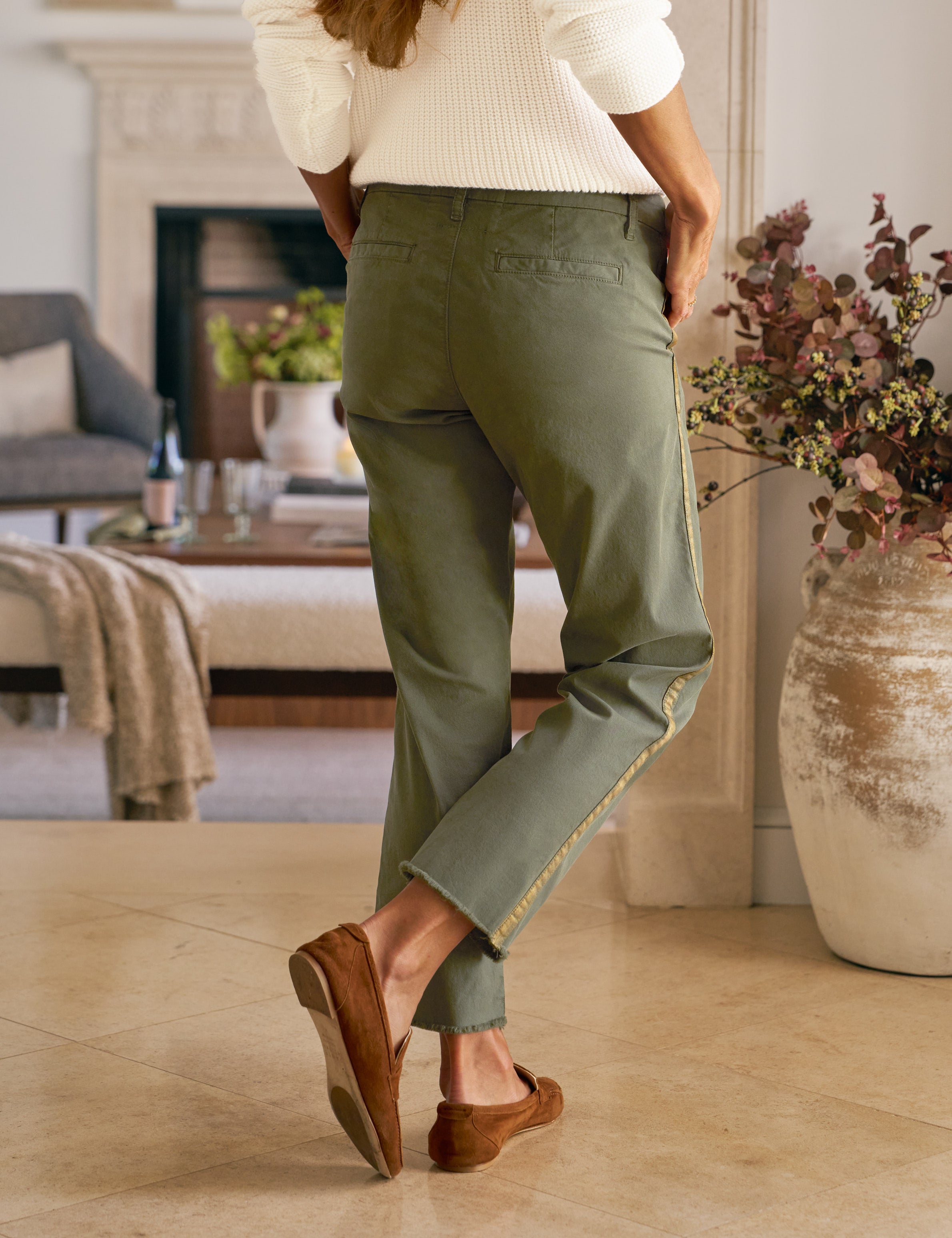 Person wearing green pants and brown shoes in a living room setting