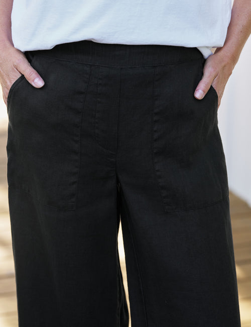 Person wearing black wide-leg pants with a white top., view 3