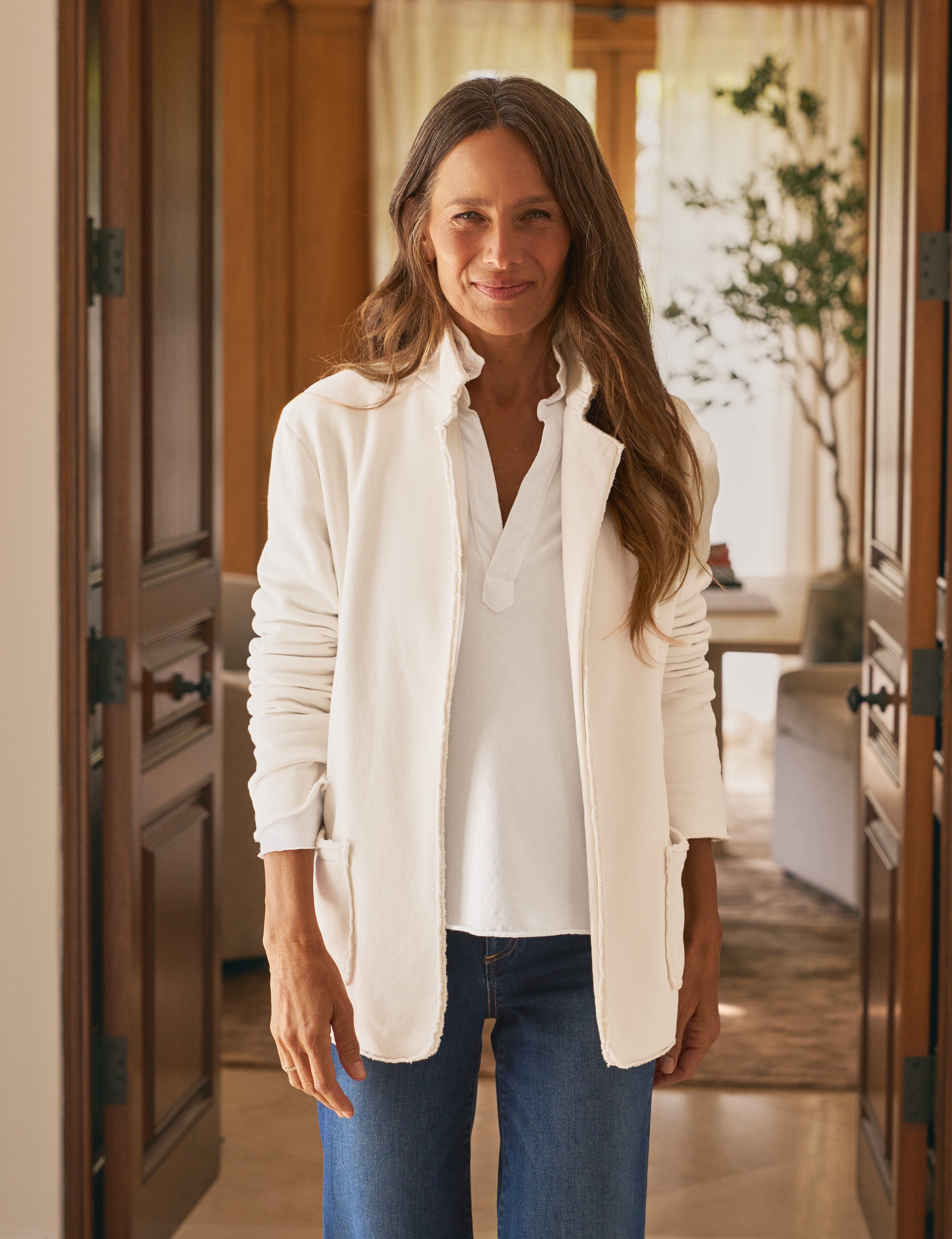 Woman wearing a white shirt and beige jacket in a kitchen setting