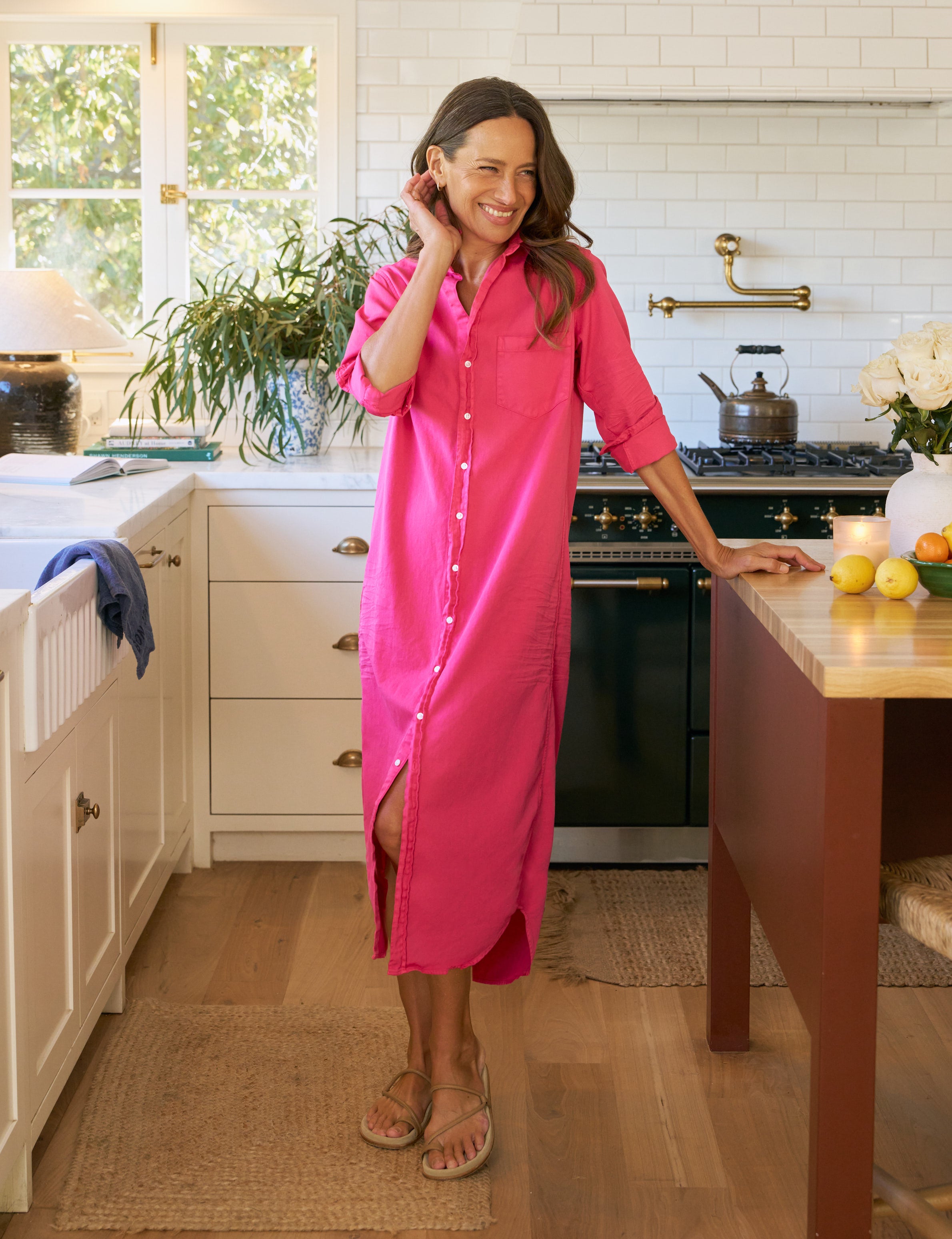 Woman in a bright pink dress standing in a kitchen.