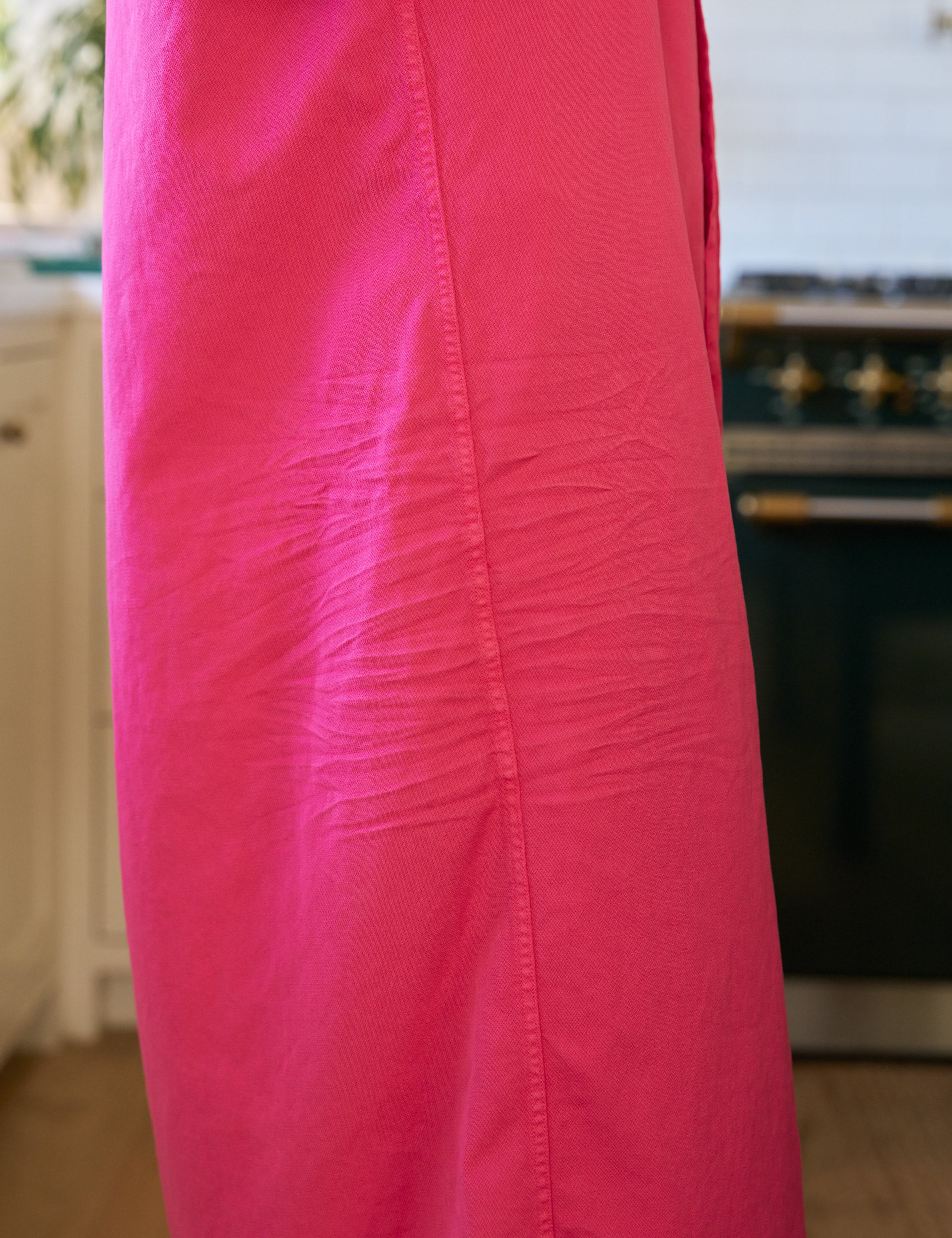 Close-up of a bright pink dress with a blurred kitchen background