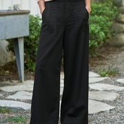 Person wearing black wide-leg pants and a beige cardigan standing outdoors.