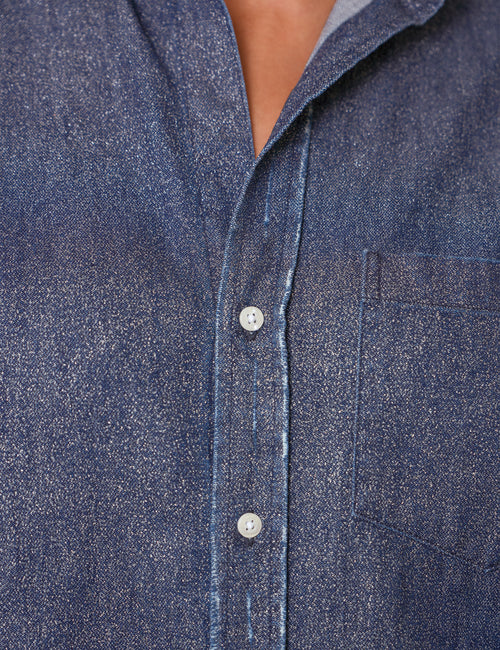 Close-up of a blue textured button-up shirt with white buttons, worn by a model., view 3