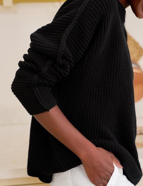 Person wearing a black sweater with a blurred background, view 3