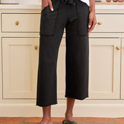Person wearing black wide-leg pants and white top in a kitchen setting