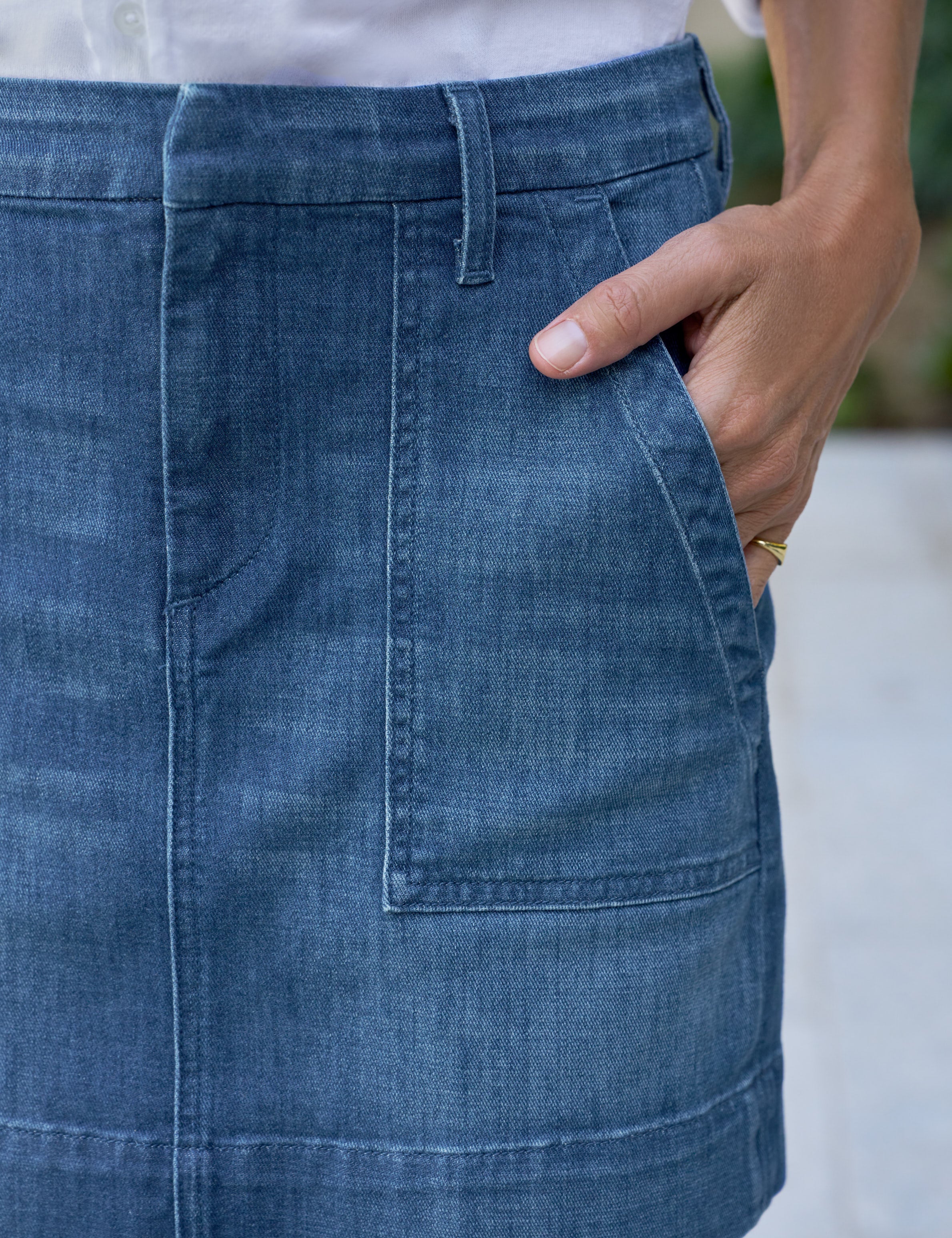Close-up of a person wearing a blue denim skirt with a blurred background, view 3