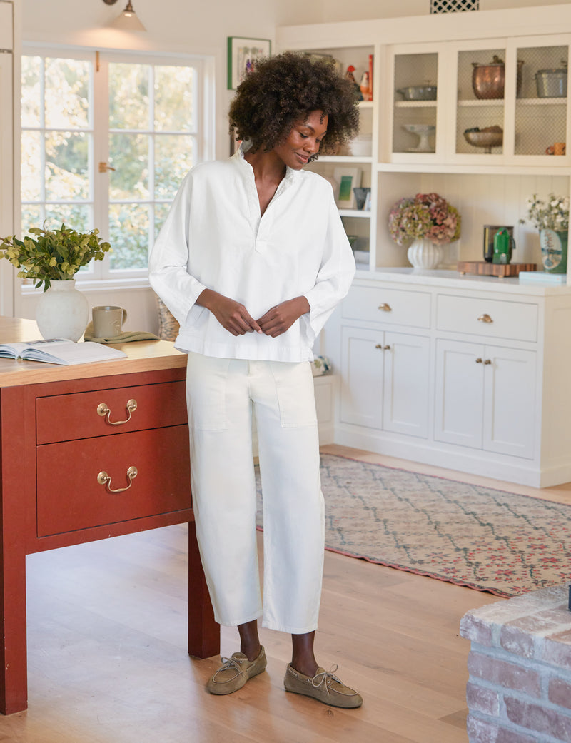 Woman in a white outfit standing in a bright kitchen with red cabinets.