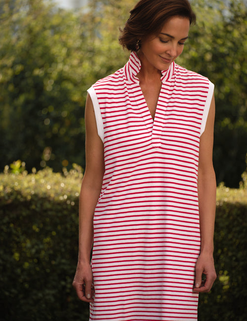 Woman wearing a red and white striped dress outdoors with greenery in the background, view 3