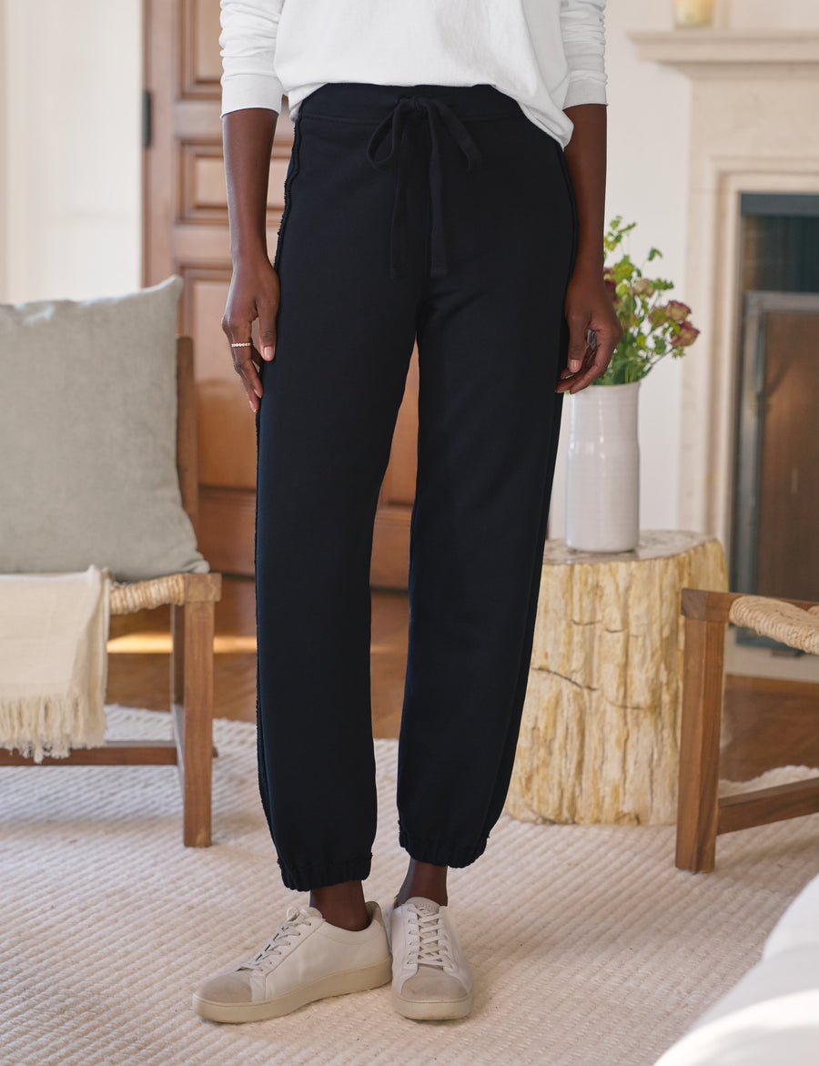 Person wearing navy pants and white sneakers in a living room setting