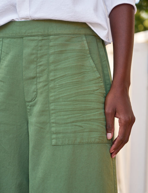 Green pants with a pocket detail worn by a person, blurred background, view 3
