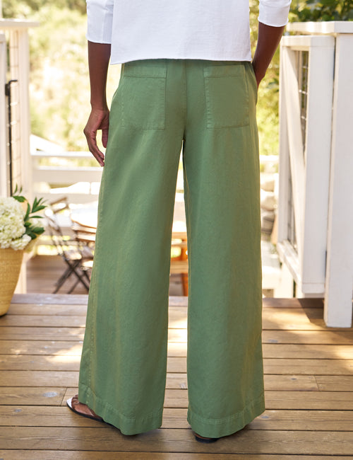 Person wearing green wide-leg pants on a wooden deck, alternate view