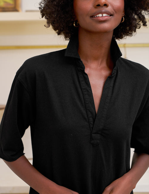 Woman wearing a black dress with a blurred background, view 3