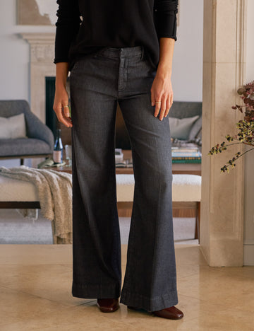 Person wearing dark gray flared pants in a living room setting