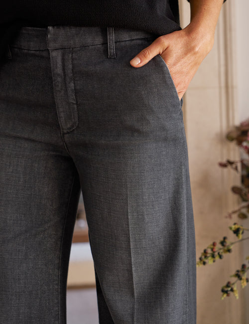 Person wearing dark gray jeans with a blurred background, view 3