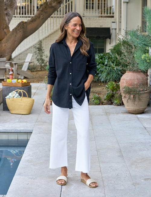 Woman in navy shirt and white pants standing by a poolside, view 4