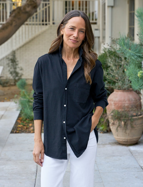 Woman wearing a navy shirt and white pants standing outdoors., front view