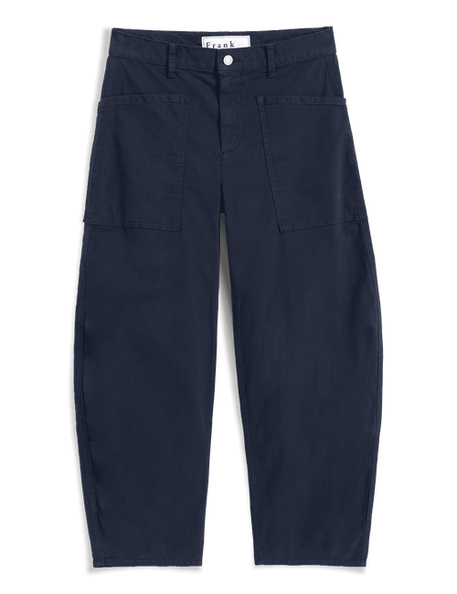 A pair of dark navy blue pants with a relaxed, slightly tapered leg, featuring two large front patch pockets and a white waistband label that reads 'Frank & Eileen'. The pants are presented flat against a solid dark green background., view 4