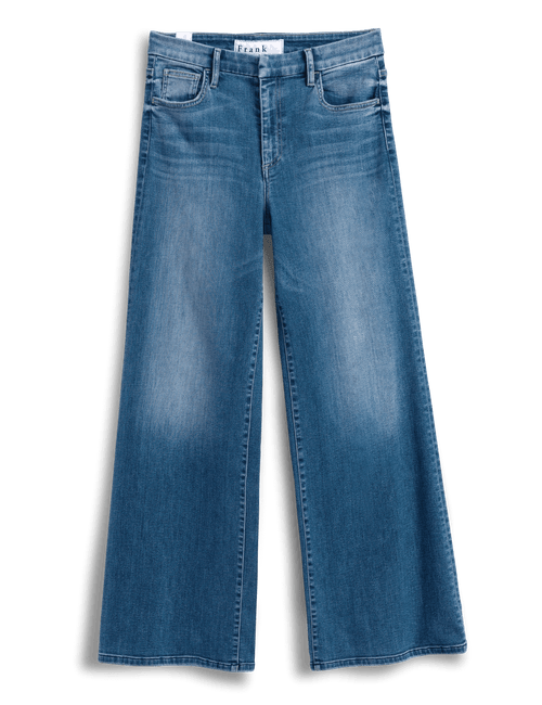 A pair of medium-wash blue denim jeans with a faded wash effect, photographed flat against a solid green background., view 4