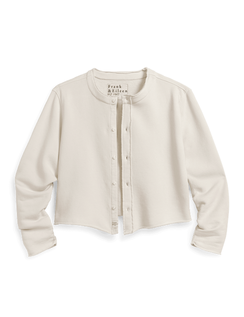 An off-white cropped button-up cardigan by Frank & Eileen, featuring a crew neck, long sleeves set against a solid dark green background., front view