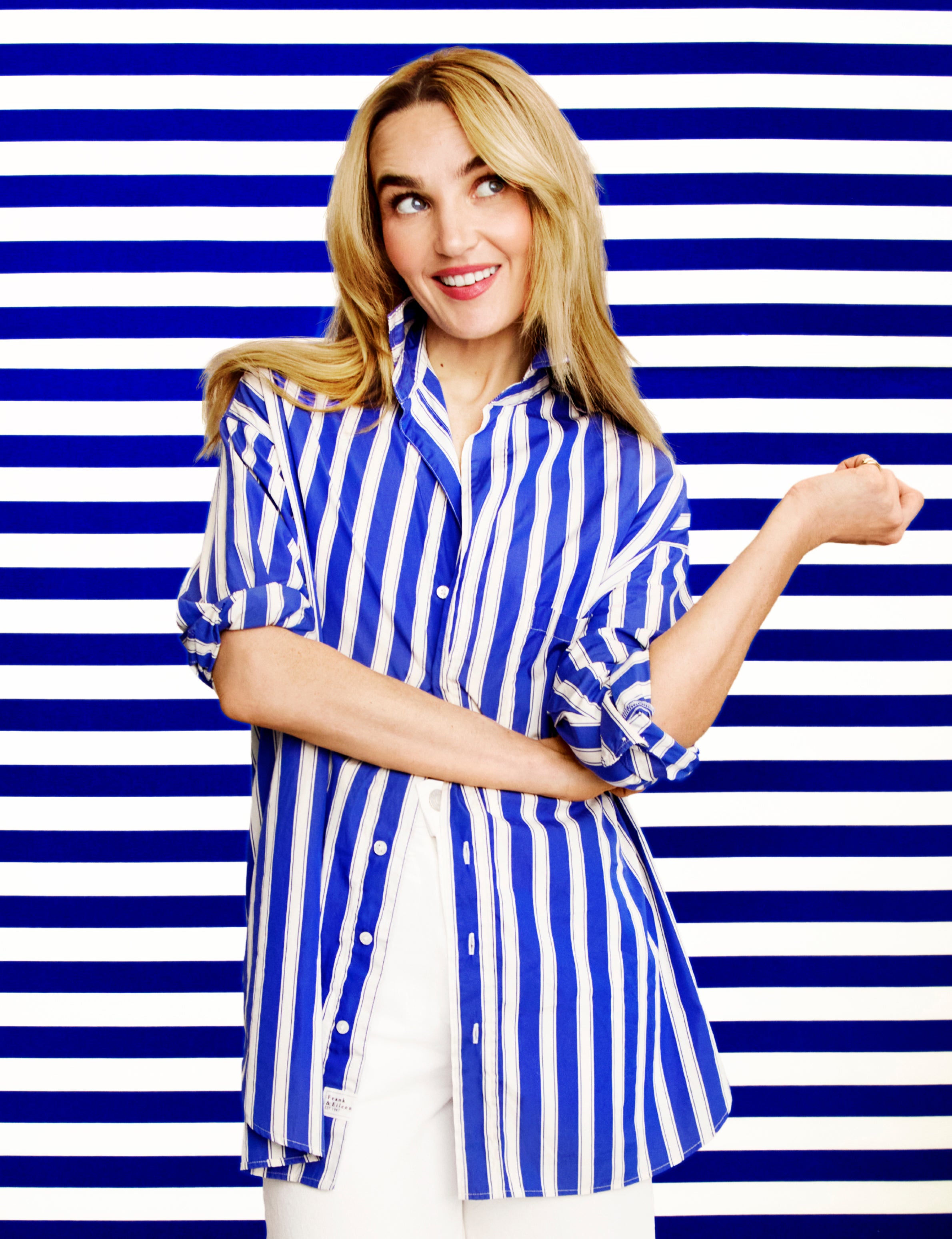 Woman wearing a blue and white striped shirt against a blue and white striped background, front view