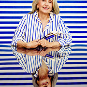 Woman in a striped shirt holding books against a blue and white striped background