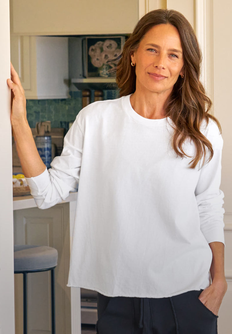 Woman wearing a white sweatshirt in a kitchen setting
